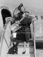 Woman with gifts climbing down airplane stairs