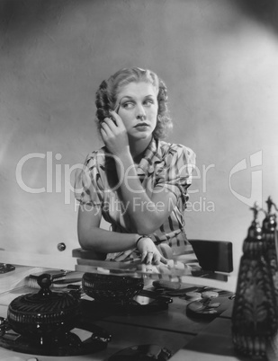 Woman applies makeup at her dressing table