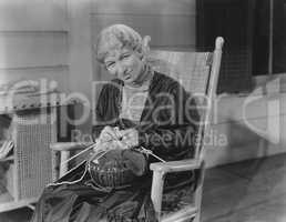 Smiling woman knitting in her rocking chair