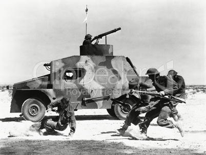 Soldiers running along side of tank in the desert
