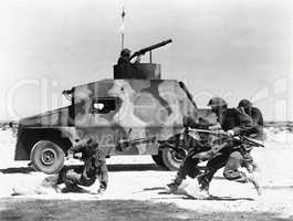 Soldiers running along side of tank in the desert