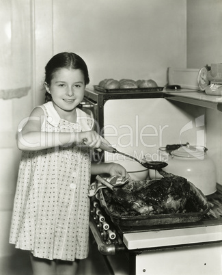 Young girl pours gravy over roast