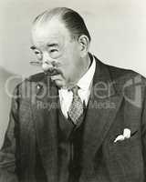 A man peers over the top of his pince-nez