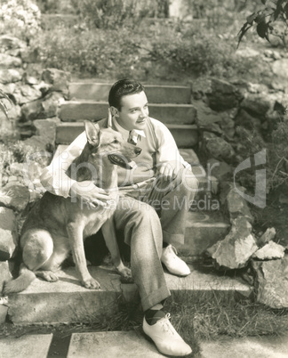 Young man sitting with dog on steps outdoors