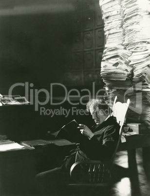 Man reading newspaper from large stack