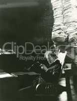 Man reading newspaper from large stack