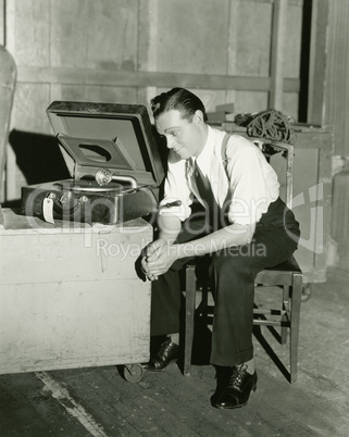 Man listening to portable gramophone