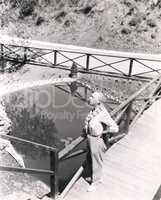 High angle view of man standing on bridge overlooking pond