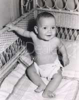 Smiling baby boy sitting in crib