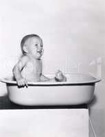 Happy baby sitting in bathtub