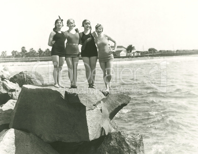 Women in bathing suits posing on rock