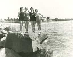 Women in bathing suits posing on rock