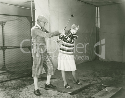 Trainer teaching woman to play golf