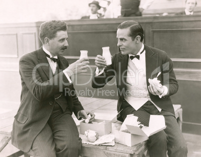 Two men toasting with milk bottles