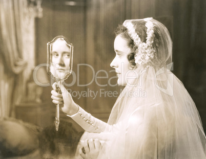 Bride gazing into hand mirror