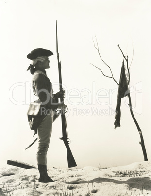 Portrait of 18th century soldier looking at flag