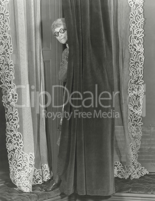 Woman eavesdropping from behind curtain