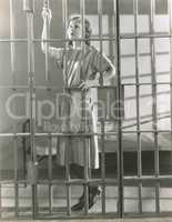 Young woman standing in prison cell