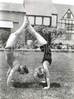 Side view of young couple doing handstands in yard