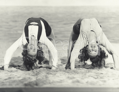 Two women doing backbends on the beach