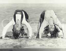 Two women doing backbends on the beach