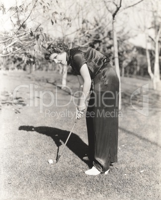 Full length portrait of young woman playing golf on field