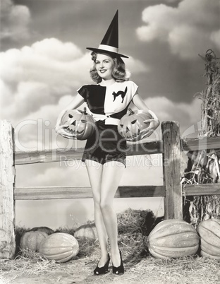 Bewitching woman carrying carved pumpkins