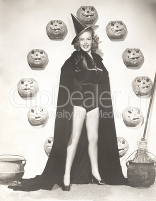 Woman in witch costume surrounded by carved pumpkins