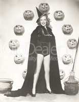 Woman in witch costume surrounded by carved pumpkins