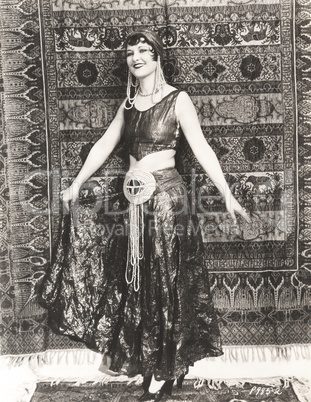 Woman dressed in gypsy costume standing in front of rug