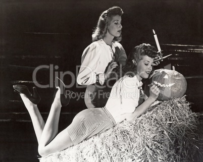 Two women in a barn carving jack o'lantern