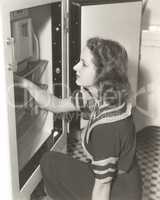 Side view of woman looking through refrigerator