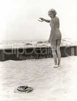 Rear view of woman playing horseshoes at the beach