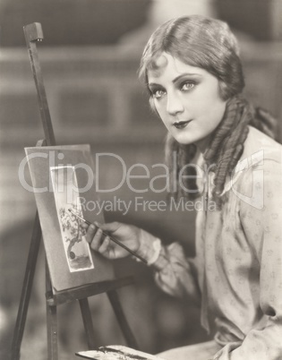 Portrait of an artist with her easel painting a picture of a tree