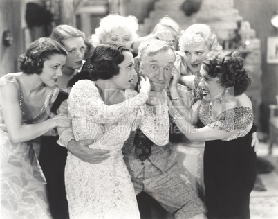 Elderly man surrounded by flirtatous young women