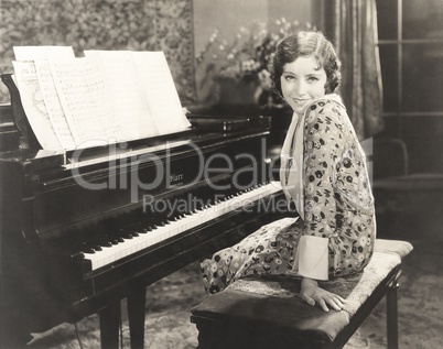 Smiling woman sitting by piano at home