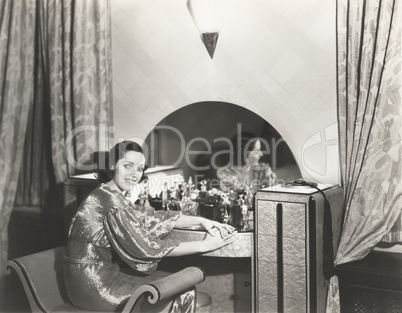 Woman in metallic dress sitting at her dressing table