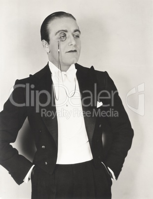 Man wearing monocle and tuxedo with hands in pockets