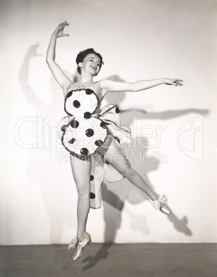 Dancer in polka dot costume leaping in mid air