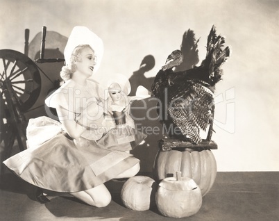 Woman holding doll wearing identical Thanksgiving costume