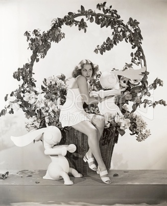Woman sitting in giant Easter basket with toy rabbits