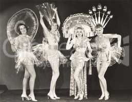 Four women wearing funny hats and costumes