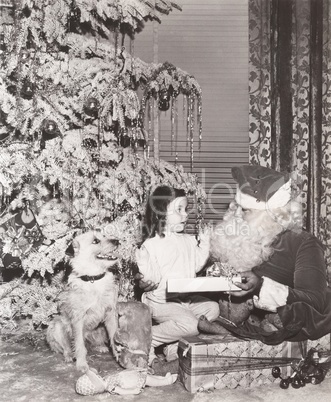 Santa Claus giving gift to little girl and her dog