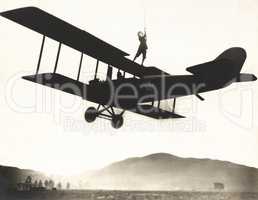 Stunt woman standing on top of biplane