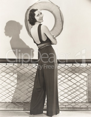 Woman in jumpsuit posing by life preserver