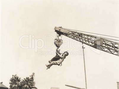 Two people dangling from crane