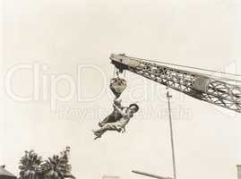 Two people dangling from crane