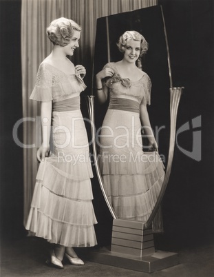 Woman in tiered dress looking at her reflection in mirror