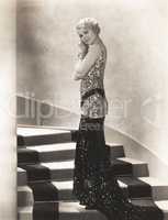 Woman in sequined gown standing on staircase
