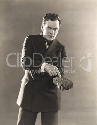 Man in suit holding a brick